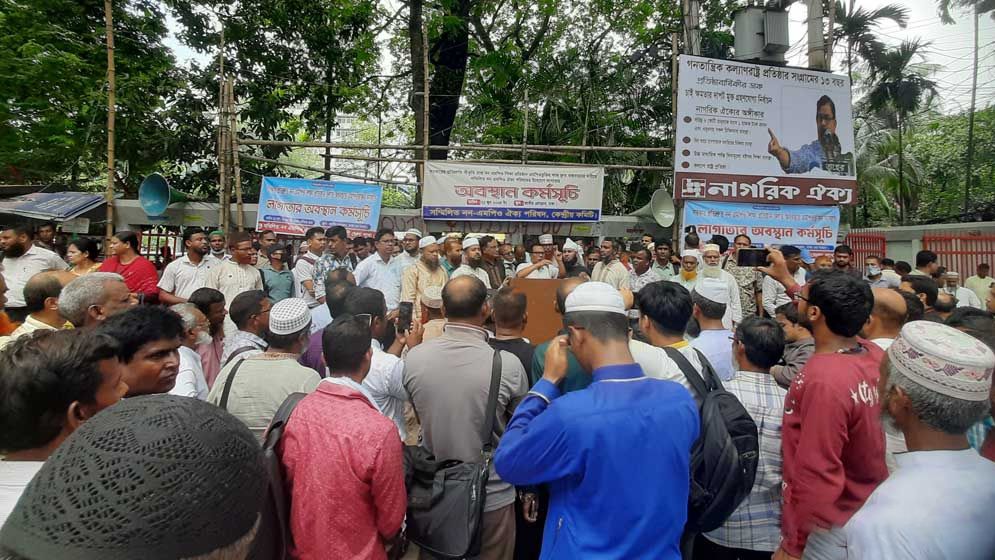 কাফনের কাপড় পরে  লাগাতার অবস্থান কর্মসূচিতে শিক্ষকরা